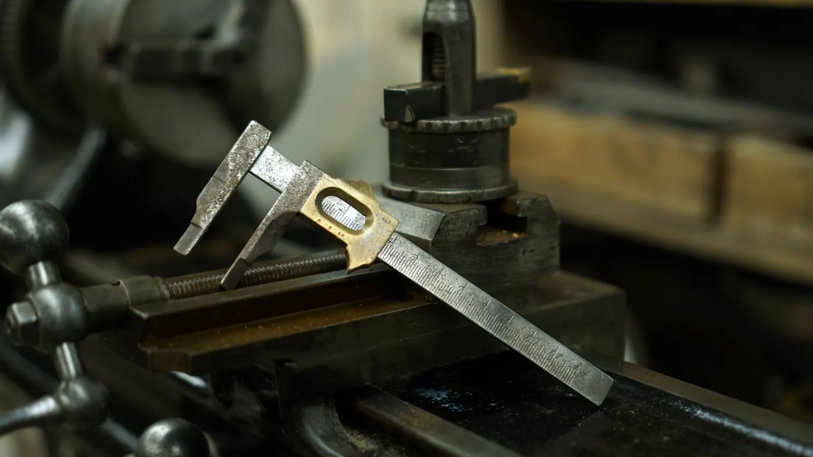 Calibro metallico appoggiato sul carrello di un tornio in un'officina