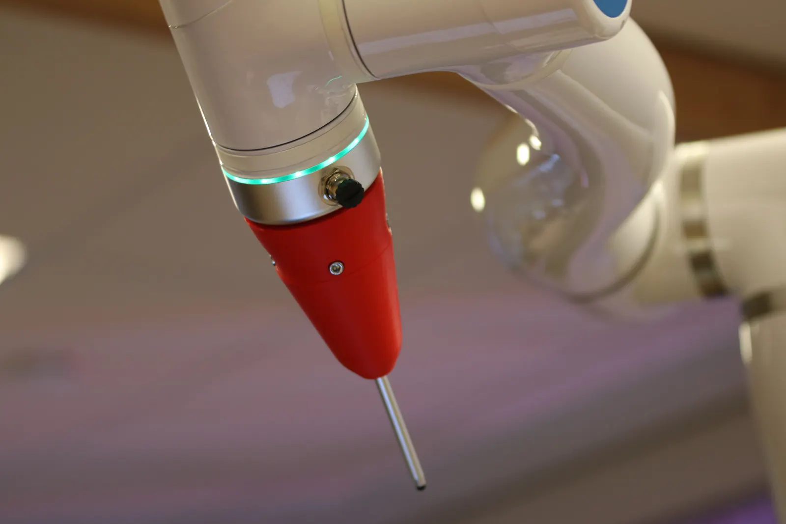 Primo piano di un braccio robotico industriale bianco con utensile rosso e sonda metallica