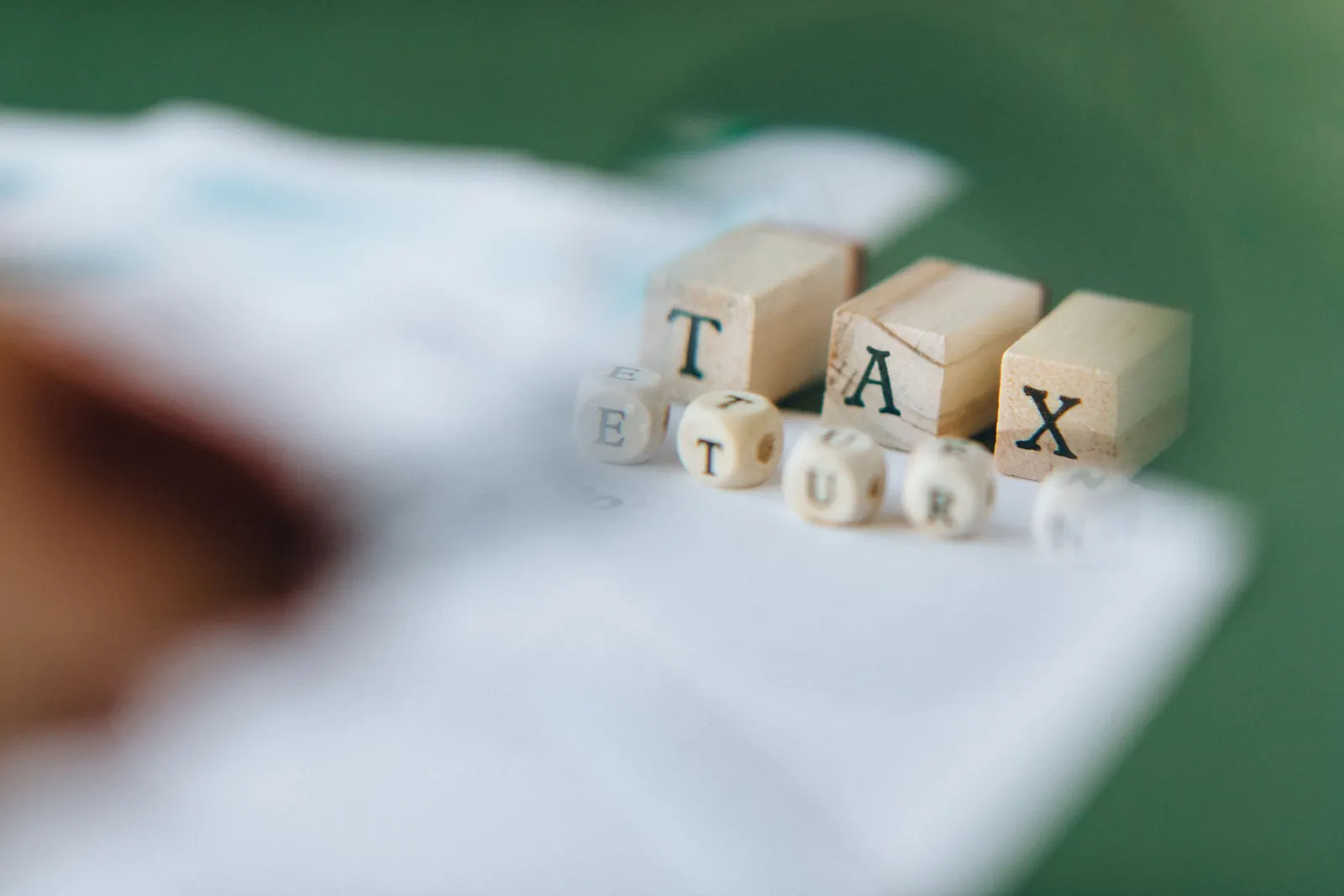 Blocchetti di legno e dado che formano la scritta Tax Return su sfondo verde sfocato